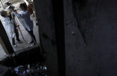 Para peneliti dari Universitas Negeri Rio de Janeiro sedang mengumpulkan sampel virus corona dari sebuah selokan terbuka di kawasan kumuh Santa Marta, di Rio de Janeiro, Brazil. (Reuters)