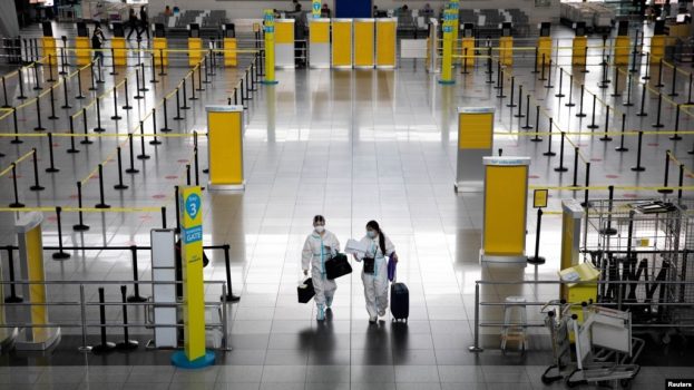 Penumpang yang mengenakan hazmat berjalan melalui Bandara Internasional Ninoy Aquino di Paranaque, Metro Manila, Filipina. (Foto: Reuters)
