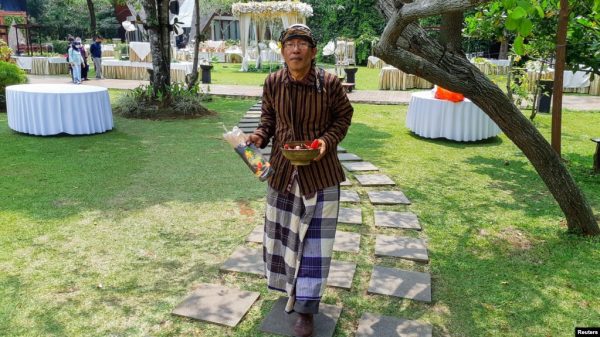Pawang hujan tradisional, Ki Joko Sapu Jagat (57), membawa sesajen dan dupa menjelang perhelatan yang akan diselenggarakan di luar ruangan di pinggiran Jakarta, 17 Oktober 2021. (REUTERS/Adi Kurniawan)
