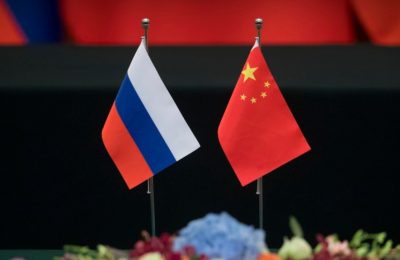 Bendera Rusia, kiri, dan China diletakkan di atas meja sebelum upacara penandatanganan di Aula Besar Rakyat di Beijing, Jumat, 8 Juni 2018. (Foto: AP)