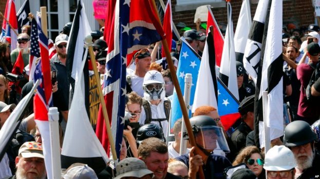 Kelompok nasionalis kulit putih berjalan menuju pinta masuk taman Lee Park yang sudah dikelilingin oleh massa dari pihak oposisi dalam aksi unjuk rasa di Charlottesville, Virginia, pada 12 Agustus 2017. (Foto: AP/Steve Helber)