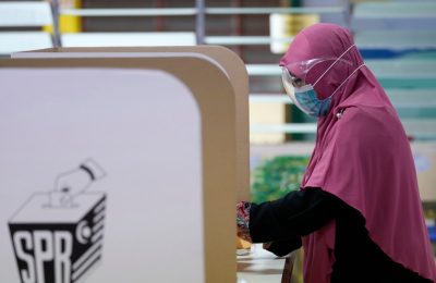Seorang perempuan melaksananakan hak pilih di sebuah tempat pemungutan suara dalam pilkada di negara bagian Melaka, Sabtu, 20 November 2021. (Foto: AP/Vincent Thian)