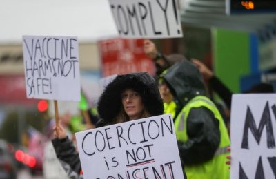 Seorang perempuan memegang poster yang berisi protes terhadap pemberlakuan mandat vaksin dalam aksi unjuk rasa di luar kantor perusahaan penerbangan Boeing di Everett, Washington, pada 15 Oktober 2021. (Foto: Reuters/Lindsey Wasson)