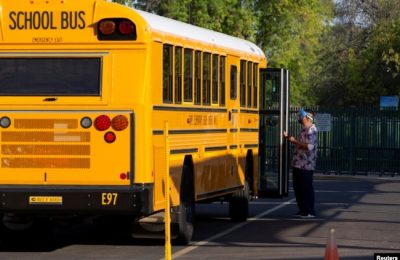 Seorang karyawan menunggu untuk membantu seorang siswa turun dari bus saat pembelajaran tatap muka dilanjutkan dengan pembatasan untuk mencegah penyebaran COVID-19 di Rover Elementary School di Tempe, Arizona, AS, 17 Agustus 2020. (Foto: Reuters)