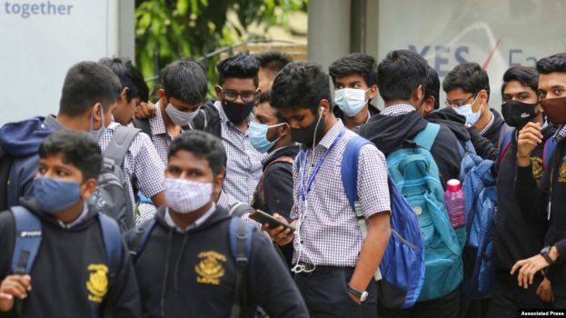 Para siswa di Bengaluru, India, menggunakan masker sebagai langkah pencegahan penularan COVID-19 saat mereka menunggu bis sekolah yang akan datang menjemput pada 30 November 2021. (Foto: AP/Aijaz Rahi)