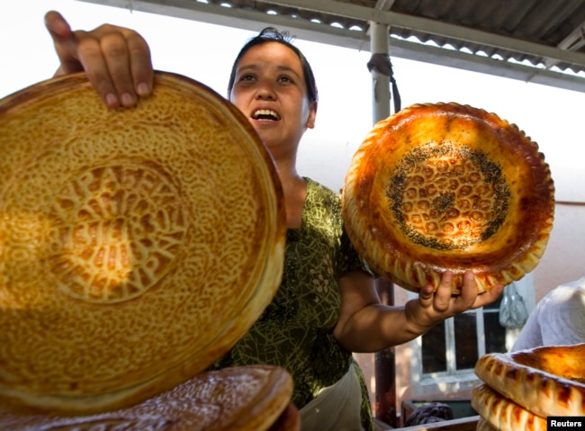 Seorang perempuan menjual roti tradisional Uzbekistan (patir) di dekat kota Kokand, 30 Agustua 2012. (REUTERS/Shamil Zhumatov)