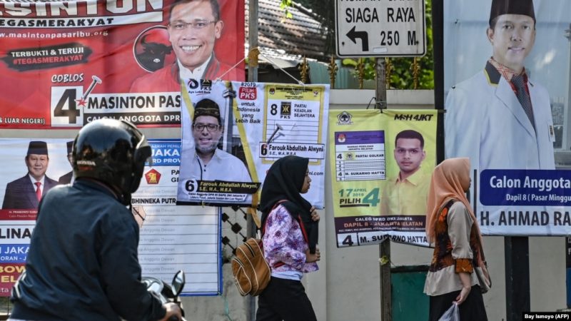 Pejalan kaki melewati spanduk kampanye Pemilu 2019 di Jakarta.(Foto: AFP/Bay Ismoyo)