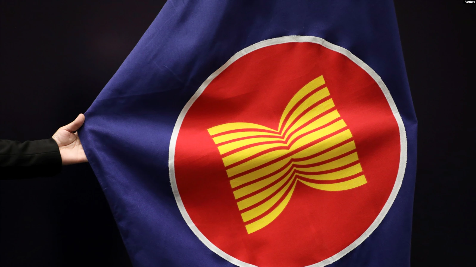 Seorang pekerja sedang membenahi bendera ASEAN di aula pertemuan di Kuala Lumpur, Malaysia, 28 Oktober 2021. (Foto: REUTERS/Lim Huey Teng)