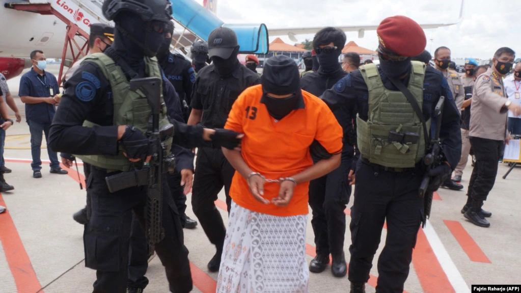 Polisi mengawal Zulkarnaen, seorang pemimpin senior Jemaah Islamiyah (JI) yang terkait dengan Al-Qaeda, yang sedang dalam pelarian karena perannya dalam Bom Bali 2002, di Bandara Internasional Soekarno-Hatta, 16 Desember 2020. (Foto: AFP/Fajrin Raharjo)