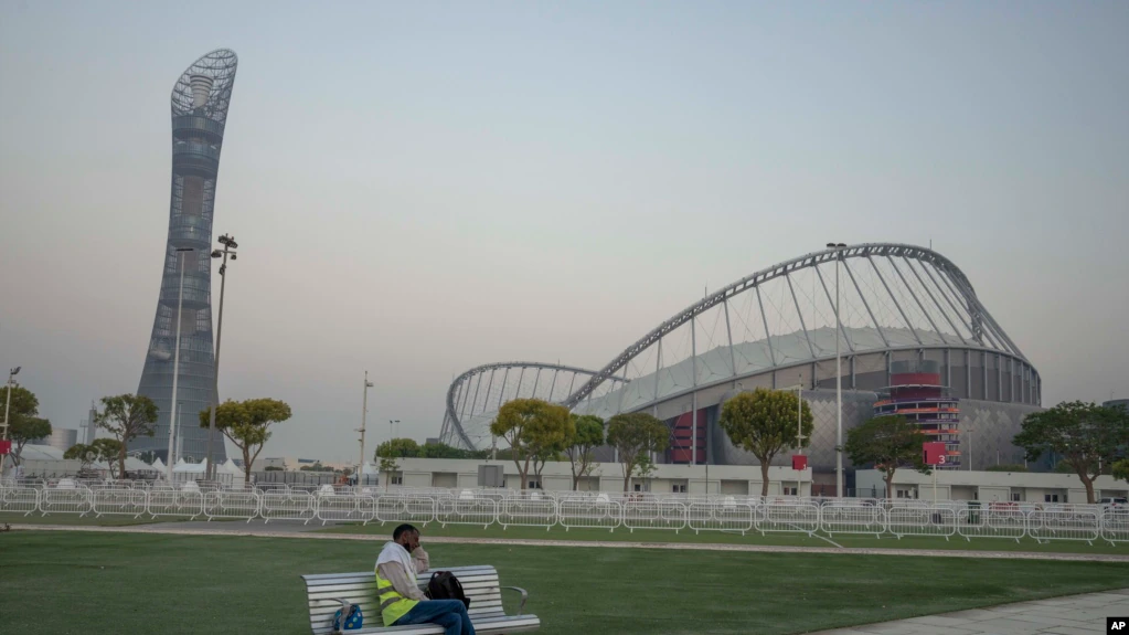 Seorang pekerja migran tertidur di bangku sebelum shift paginya, di depan Stadion Internasional Khalifa, stadion nasional dan tertua Qatar, yang akan menjadi tuan rumah pertandingan selama Piala Dunia FIFA 2022, di Doha, Qatar, Sabtu, 15 Oktober. 2022. (AP Photo/Nariman El-Mofty)