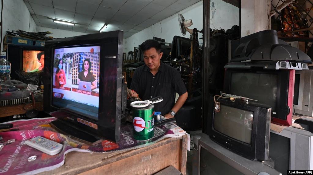 Ilustrasi - Seorang pria memperbaiki pesawat televisi di bengkelnya di Jakarta, 21 Maret 2022. (AFP/Adek Berry)