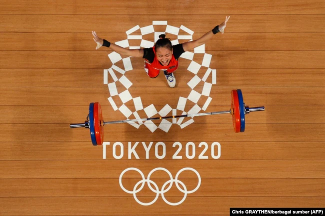 Atlet Indonesia Windy Cantika Aisah saat berlaga di cabang olahraga angkat besi 49 kg putri di Olimpiade Tokyo 2020, 24 Juli 2021. (Foto: Chris GRAYTHEN/berbagai sumber/AFP)