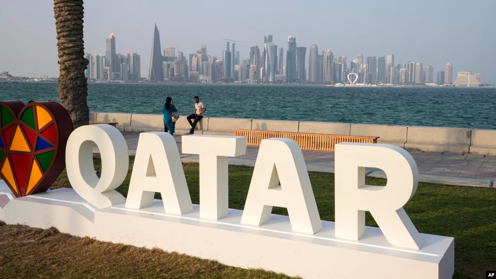 Dua orang difoto di Doha Corniche di depan kaki langit modern sehari sebelum dimulainya Piala Dunia Sepak Bola di Doha, Qatar, Sabtu, 19 November 2022. (Foto: AP/Martin Meissner)