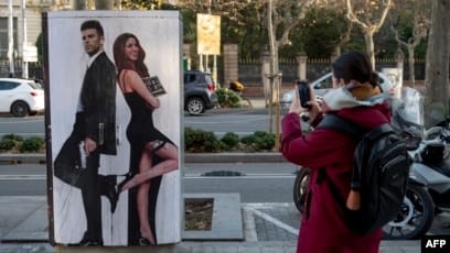 Seorang pejalan kaki memotret mural bergambar mantan bek Spanyol Barcelona Gerard Pique dan penyanyi Kolombia Shakira hasil karya seniman jalanan Italia Salvatore Benintende alias TvBoy di Barcelona, 13 Januari 2023. (Josep LAGO / AFP)