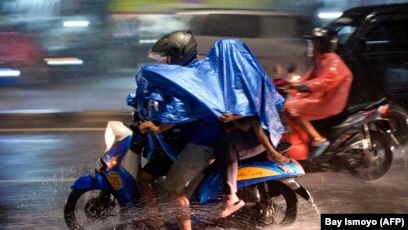 Pengendara motor mengenakan jas hujan saat berkendara saat hujan deras mengguyur Ibu Kota Jakarta pada 19 Januari 2022. (Foto: BAY ISMOYO/AFP)