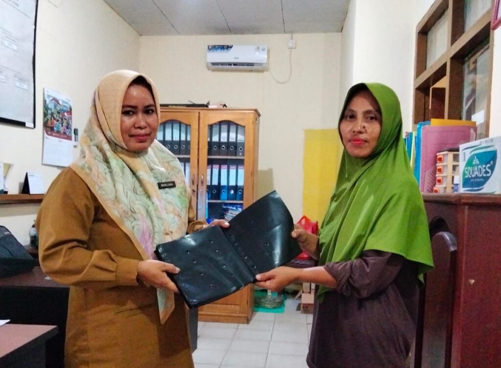 Kasi PMKS Kelurahan Petung, Marliana (kiri) membagikan polybag kepada perwakilan kelompok dasawisma RT 05, Kelurahan Petung, Kecamatan Penajam, Kabupaten PPU. (Ist)