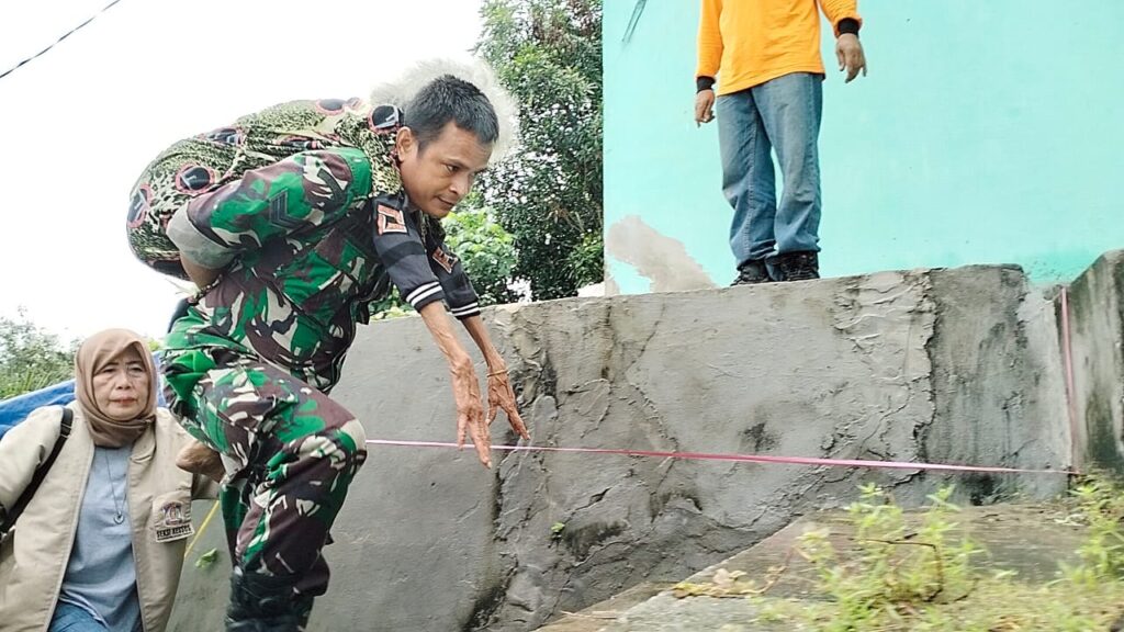 Babinsa Sertu Taufik Hadi Gendong Korban Tanah Longsor. (Ist)