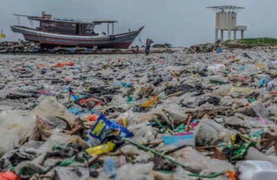 Warga berjalan diatas tumpukkan sampah plastik di Pantai Labuan, pandeglang, Banten, Selasa (12/12/2023).