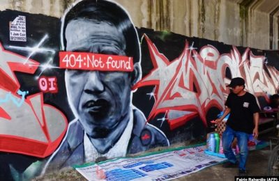 Sebuah mural yang menggambarkan Presiden Indonesia Joko Widodo dengan pesan kesalahan jaringan "404: tidak ditemukan" menutupi matanya, di Tangerang, Banten, sebelum dihapus dan polisi melakukan penyelidikan terkait hal tersebut. (Foto: AFP/Fajrin Rahardj