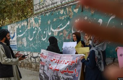 Seorang anggota pasukan Taliban berbicara dengan perempuan yang melakukan unjuk rasa di luar salah satu sekolah di Kabul, Afghanistan, pada 30 September 2021. (Foto: AFP/Bulent Kilic)