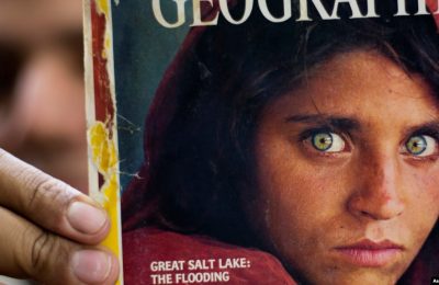 Pemilik sebuah toko buku di Islamabad, Pakistan, Inam Khan, tampak menunjukkan majalah National Geographic yang menampilkan Sharbat Gulla di sampul depannya dalam foto yang diambil pada 26 Oktober 2016. (Foto: AP/B.K. Bangash, File)