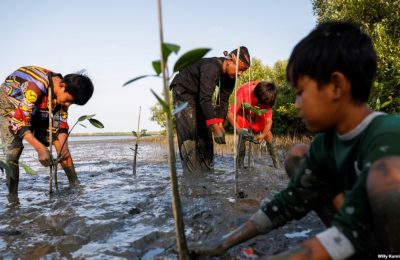 Seorang laki-laki bernama Samsudin sedang menanam pohon-pohon bakau bersama anak-anak di Pantai Tiris, Desa Pabeanilir, Kabupaten Indramayu, Jawa Barat, 11 Maret 2021. (Foto: Willy Kurniawan/Reuters)