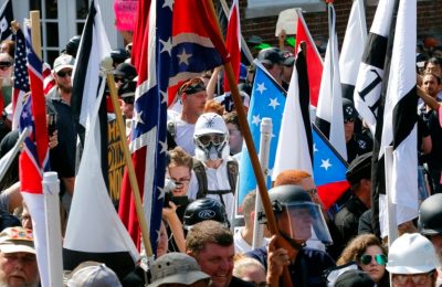 Kelompok nasionalis kulit putih berjalan menuju pinta masuk taman Lee Park yang sudah dikelilingin oleh massa dari pihak oposisi dalam aksi unjuk rasa di Charlottesville, Virginia, pada 12 Agustus 2017. (Foto: AP/Steve Helber)