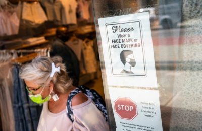 Seorang pelanggan yang mengenakan masker keluar dari toko di Broadway di distrik perbelanjaan ritel di lingkungan SoHo di wilayah Manhattan, New York, Jumat, 14 Mei 2021.. (Foto: AP)