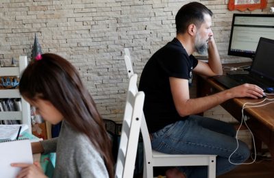 Csaba Posta (kanan), seorang ahli IT, bekerja dari rumahnya bersama dengan anaknya Vilma yang tengah belajar dari rumah mereka di di Budapest, Hungaria, pada 19 Maret 2020. (Foto: Reuters/Bernadett Szabo)