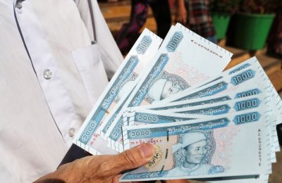 Seorang pria menunjukkan uang kertas baru yang dicetak dengan potret Jenderal Aung San, mendiang ayah pemimpin Myanmar Aung San Suu Kyi, di luar Bank Ekonomi Myanmar Selasa, 7 Januari 2020, di Yangon, Myanmar. (Foto: AP)