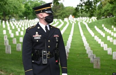 Seorang tentara AS berdiri di depan jajaran makam dari tentara AS yang tak dikenal yang meninggal dalam beberapa perang seperti Perang Dunia I dan II serta Perang Vietnam, dalam sebuah acara di kompleks pemakaman di Arlington, Virginia pada 25 Mei 2020. (Foto: Reuters/Erin Scott