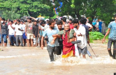 Warga melewati jalanan yang tergenang banjir di Nellore, di negara bagian Andhra Pradesh, India selatan, 20 November 2021.