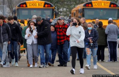 Para orang tua menjauh dari lokasi penembakan bersama anak-anak mereka pasca insiden penembakan di Oxford High School di kota Oxford, Michigan, Selasa (30/11).