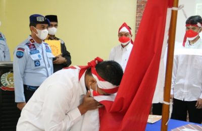 Satu dari delapan narapidana terorisme di Sumut sedang mencium bendera Merah Putih, Rabu 9 Maret 2022. (Courtesy: Humas Kemenkumham Sumut).