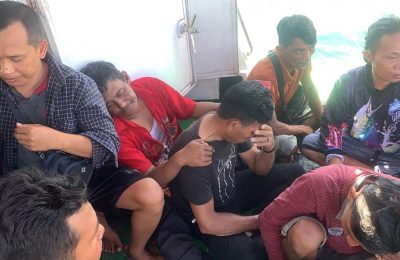 Pekerja migran asal Indonesia tampak terduduk lemas di kapal milik tim SAR setelah berhasil diselamatkan dari laut di Sumatra Utara ketika feri yang mereka tumpangi tenggelam pada 19 Maret 2022. Feri tersebut hendak bergerak menuju Malaysia. (Foto: Handout/Search and Rescue/AFP)
