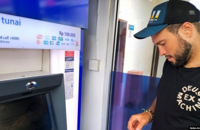 Konstantin Ivanov, warga Rusia, memegang kartunya untuk menarik uang di mesin ATM di Kuta, Bali, (Foto: REUTERS/Sultan Anshori)