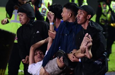 Sekelompok pria tampak membopong salah satu rekannya setelah kekisruhan meletus selepas pertandingan sepak bola antara Arema dan Persebaya di stadion Kanjuruhan, Malang, pada 1 Oktober 2022. (Foto: AFP)