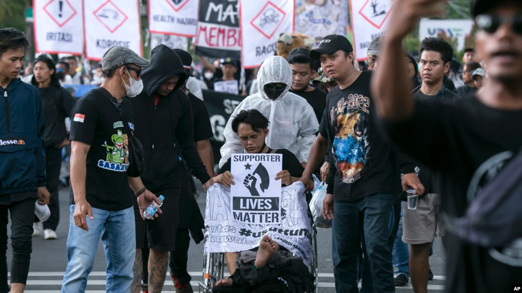 Seorang pengunjuk rasa duduk di kursi roda yang menggambarkan korban penyerbuan sepak bola 1 Oktober, dalam aksi unjuk rasa memperingati 40 hari tragedi stadion sepak bola Kanjuruhan di Malang, Jawa Timur, Kamis, 10 November 2022. (AP/Rizki Dwi Putra)