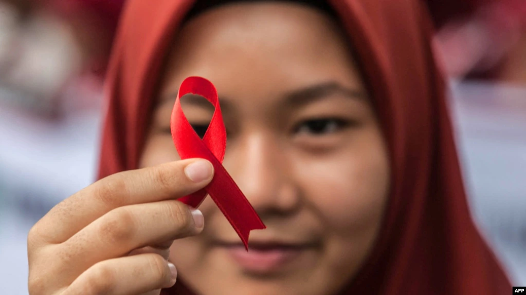 FILE - Seorang pelajar Indonesia memegang pita merah sebagai bagian dari acara kesadaran pada peringatan Hari AIDS Sedunia di Medan, provinsi Sumatera Utara, 2 Desember 2018. -(Albert Ivan Damanik/AFP)