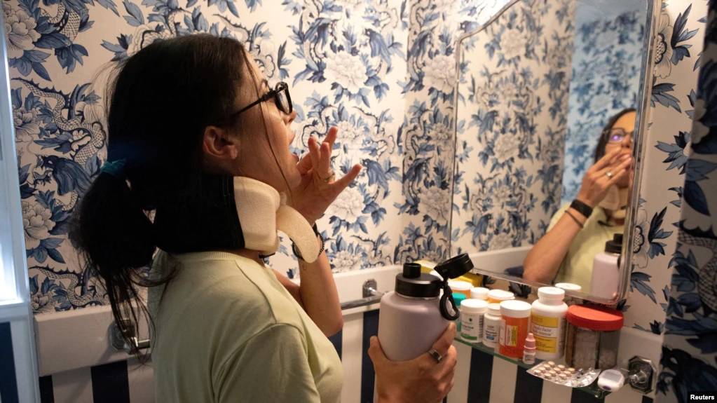 Lauren Nichols, yang memiliki gejala long COVID, menelan obat untuk gejala yang ia derita di rumahnya di Andover, Massachusetts, pada 3 Agustus 2022. (Foto: Reuters/Lauren Owens Lambert)