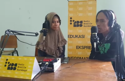 Salah satu inisiator Radio Braille Surabaya, Hanan Abdullah (kiri), sedang berbincang dengan Eben Haezer, Ketua AJI Surabaya, mengenai Hari Disabilitas Internasional. (Foto: VOA/Petrus Riski)