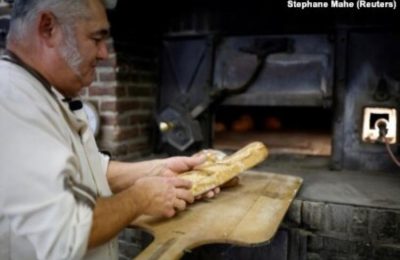Pembuat roti Prancis Franck Burgaud mengeluarkan nampan roti dari oven berbahan bakar kayu di toko roti "Au veritable four a bois" di Challans, Prancis, 5 Januari 2023. (Foto: REUTERS/Stephane Mahe)