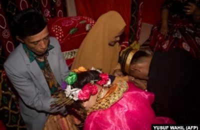 Dua remaja meminta restu orang tua setelah menikah di desa Tampapadang di Mamuju, Sulawesi Barat. (Foto: AFP)