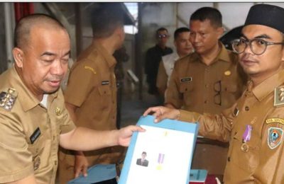 Bupati Seruyan Yulhaidir menyematkan lencana sekaligus penyerahan piagam penghargaan kepada Kepala Desa Terawan Wahyudinor. (Ist)